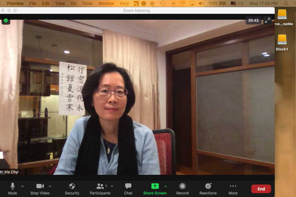 screenshot of a Zoom meeting with only one attendee as an Asian woman in a blue shirt sitting at a table