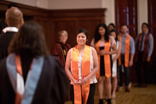 Woman stands in the front of a line with a UT burnt orange stole