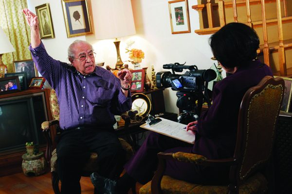 image of elderly man getting interviewed by someone who is behind a camera. Elderly man seems to be referring to the height of something.