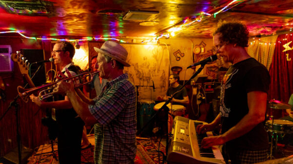 a group of men in a room with low lights playing multiple instruments