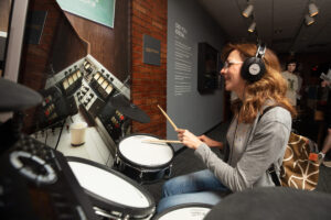 A woman plays a drumkit.