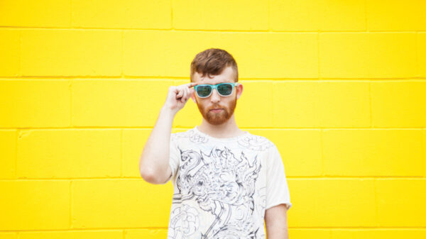 A man with sunglasses against a yellow background