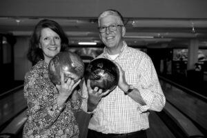 black and white image of a man and woman holding bowling balls