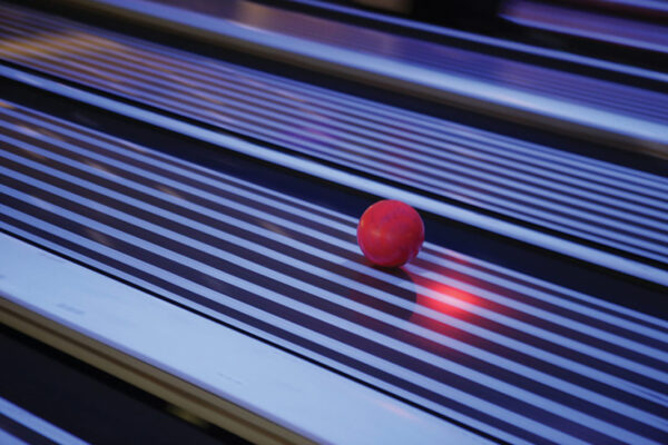purple tinted image of a bowling ball rolling in the lane.