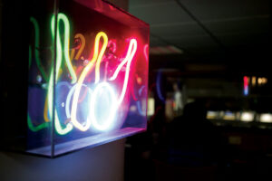 green, yellow, pink, and white neon sign of bowling pins and bowling balls in a dark room