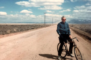 Vintage photo of Peter LaSalle standing on his bike on a dirt road in the Mexican desert