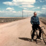 Vintage photo of Peter LaSalle standing on his bike on a dirt road in the Mexican desert