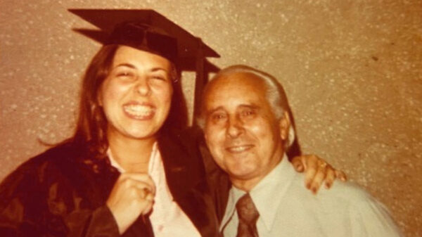 Old photo of Sarita Brown in her graduation gown standing with her father