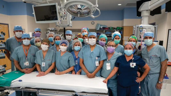 Medical professionals stand together in an operating room for a group photo