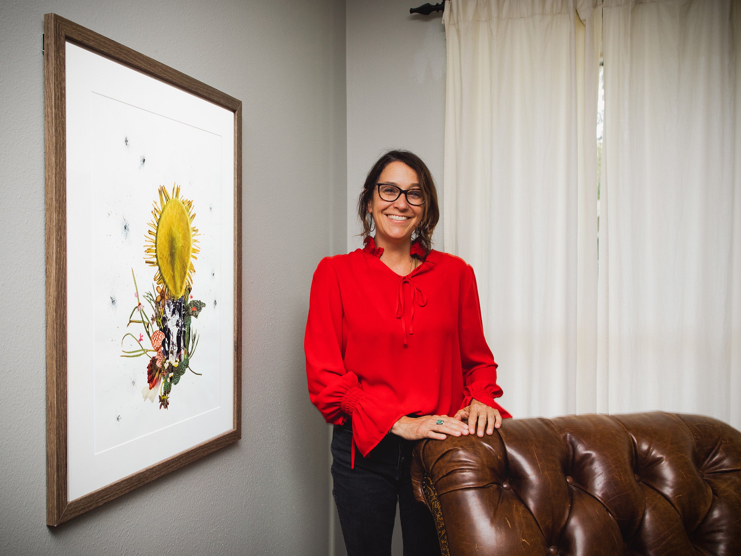 Laura Klopfenstein, smiling into the camera, stands next to her art