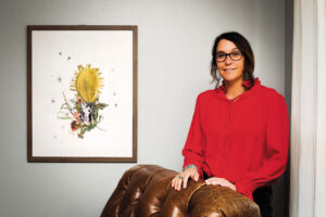 Laura Klopfenstein stands next to her art that's framed on the wall