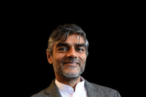 Portrait of Raj Patel smiling in front of a black background