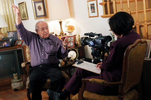 An interview is conducted inside an older man's home