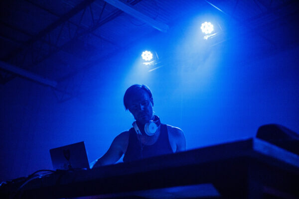 DJ at laptop with blue lights behind him