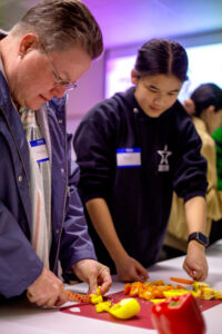 An instructor teaches a student how to chop ingredients