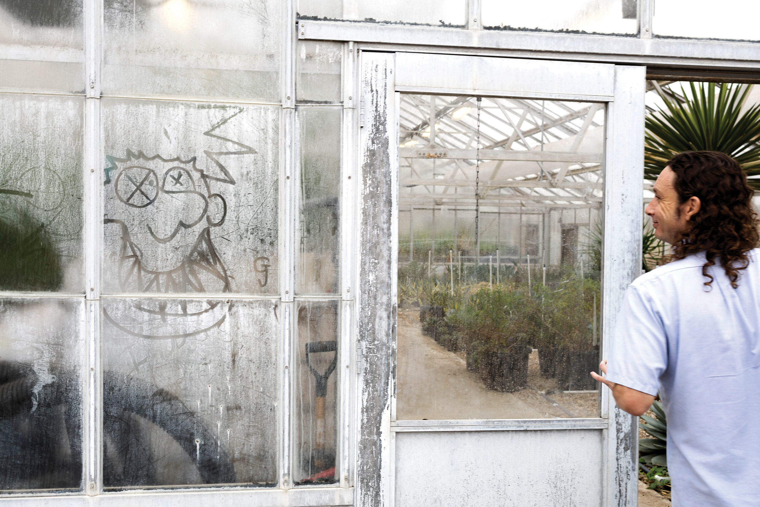 Kasey smiles at a drawing made into the fog on the glass of a greenhouse