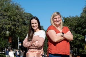 Two women stand together with arms crossed