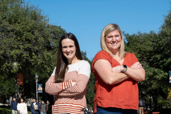 Two women stand together with arms crossed