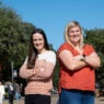Two women stand together with arms crossed